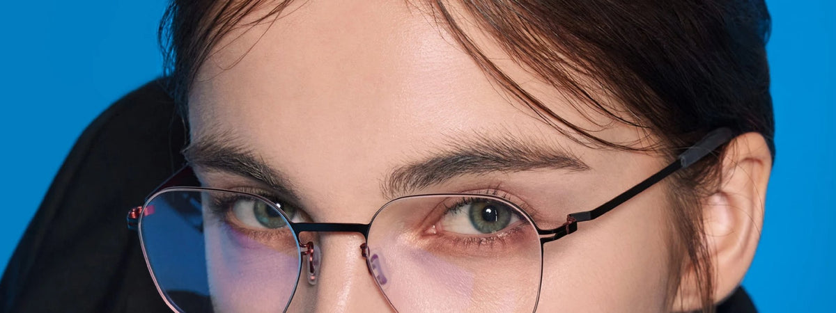 Woman in VYCOZ glasses against a cobalt wall