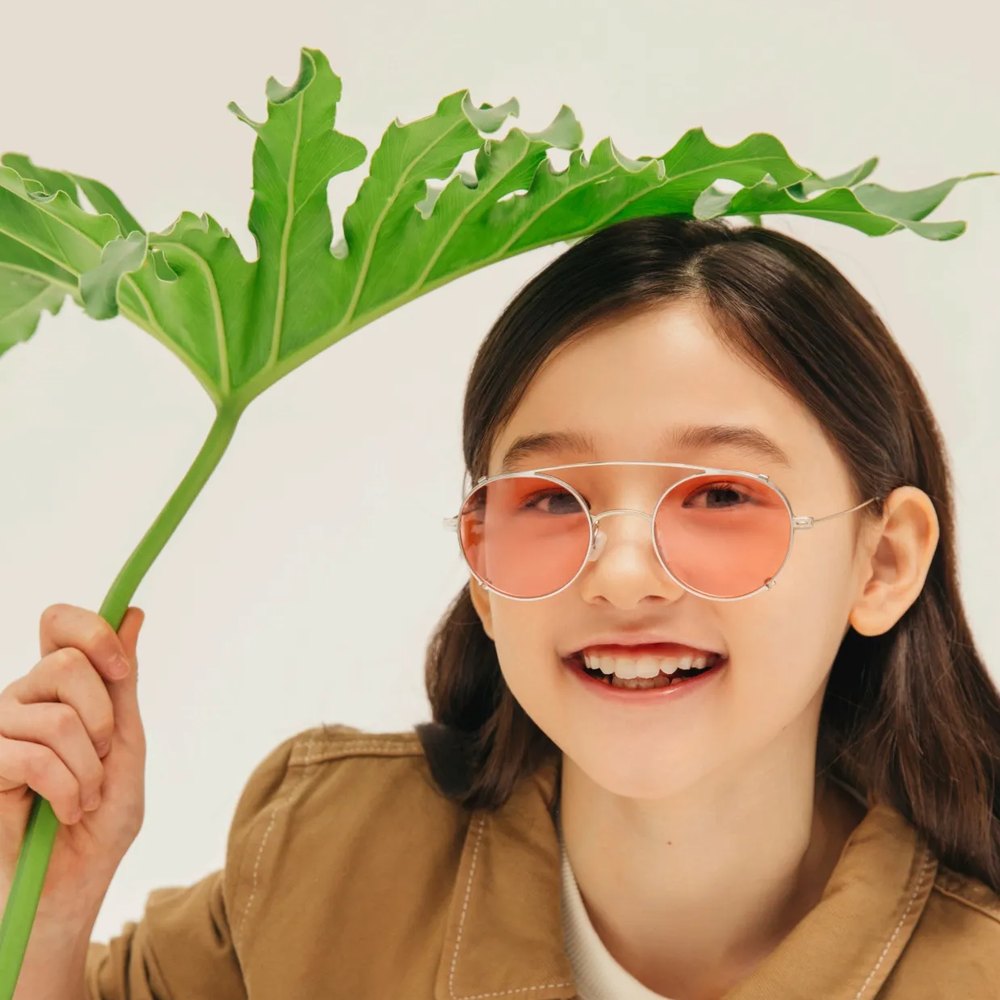 Girl in VYCOZ kids glasses holding a green leaf