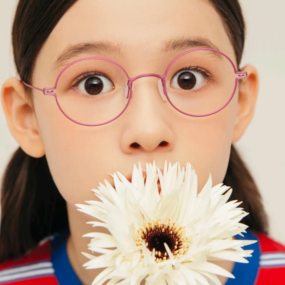 Girl in VYCOZ kids glasses holding a white flower
